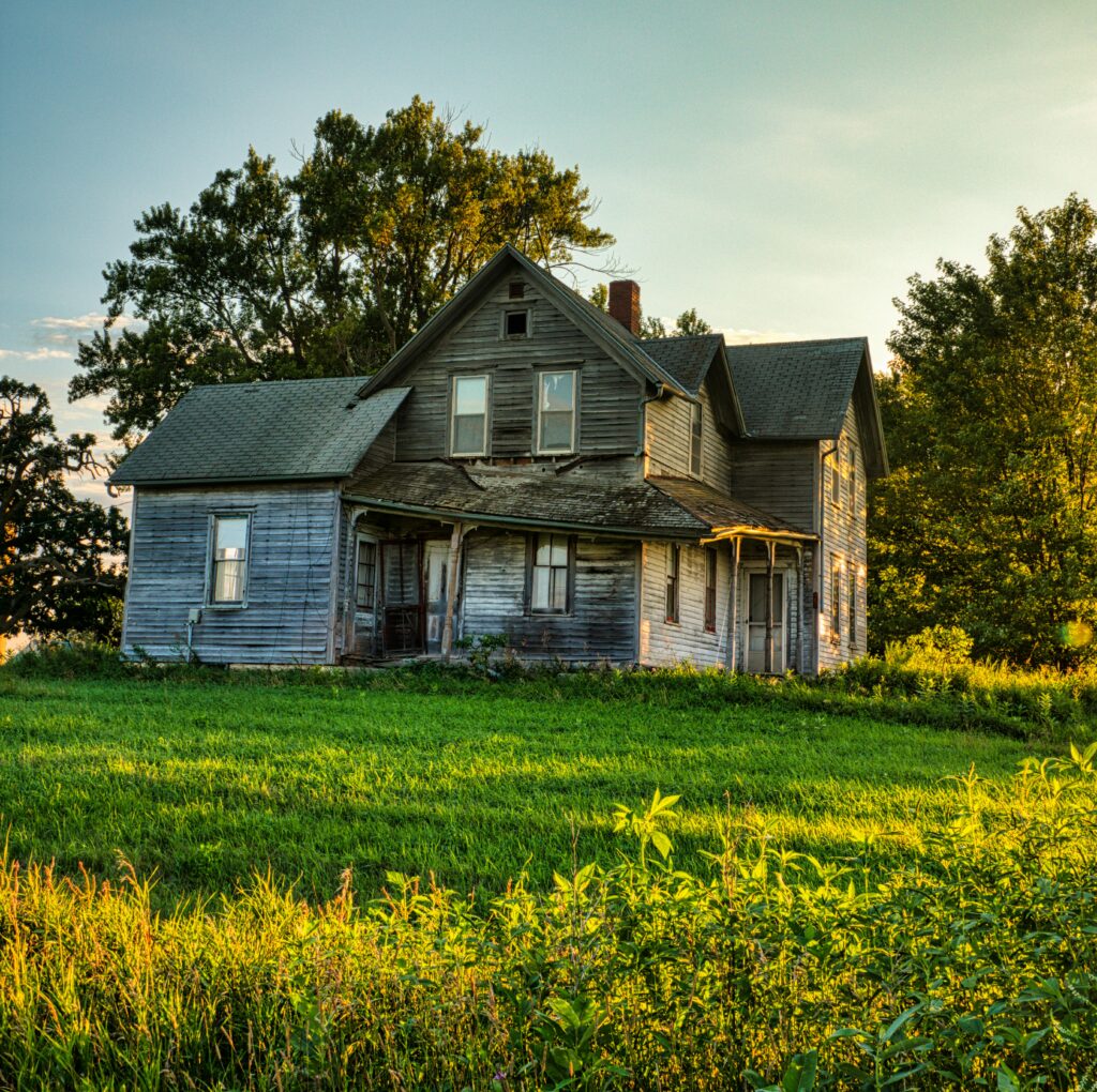A rustic wooden farmhouse surrounded by vibrant summer greenery in Minnesota.