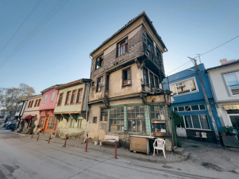 Capture of weathered townhouses along an urban street corner, showcasing architectural decay and vibrant facades.