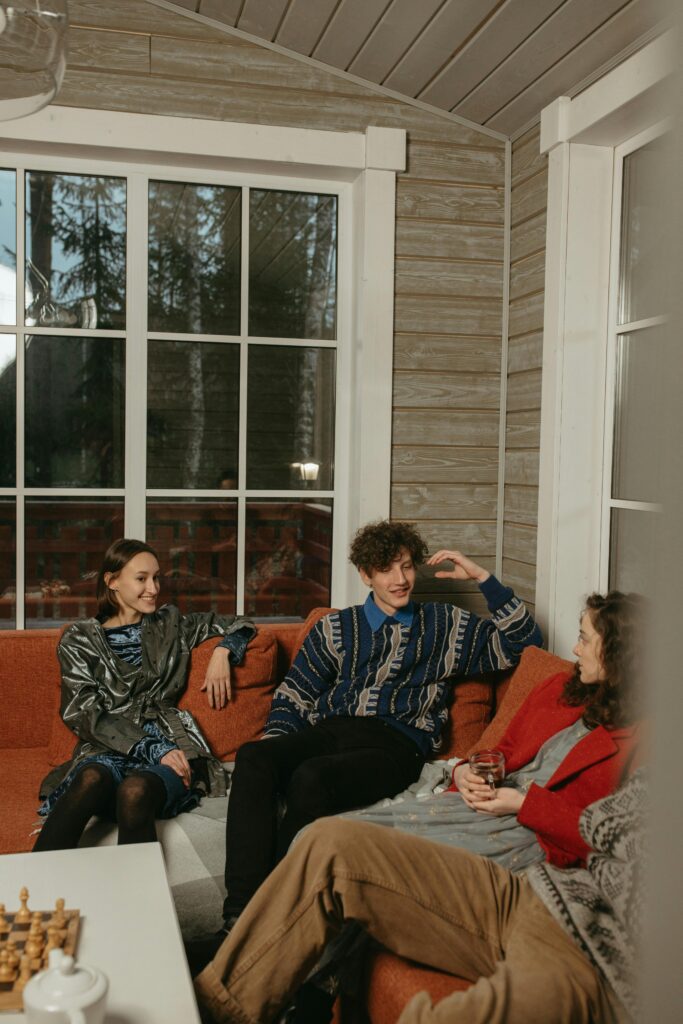 Three adults chatting in a cozy cabin interior with a warm atmosphere.